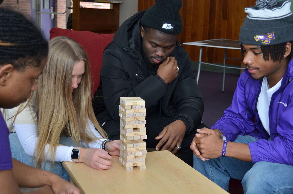 Four students play Jenga in a residence hall lounge